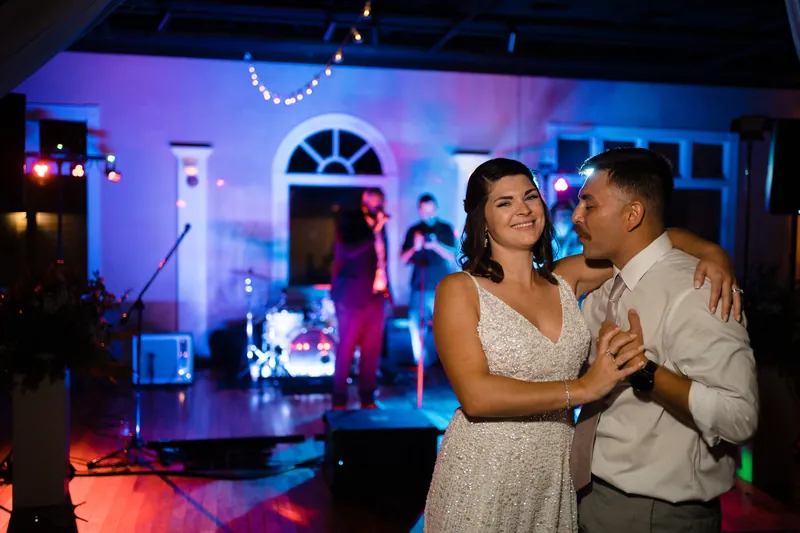Laurel and Jake dance together under purple and blue lights at The White Room, surrounded by guests.