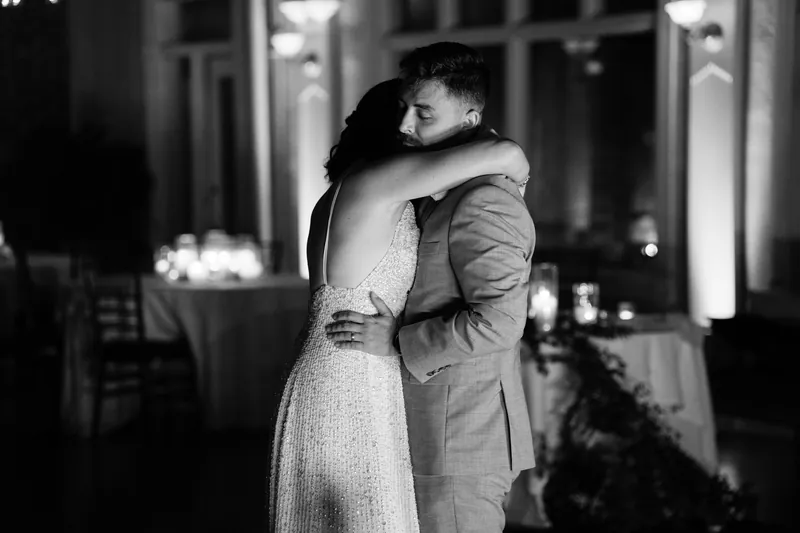 Jake and Laurel embrace in black and white, silhouetted against the lit venue behind them.