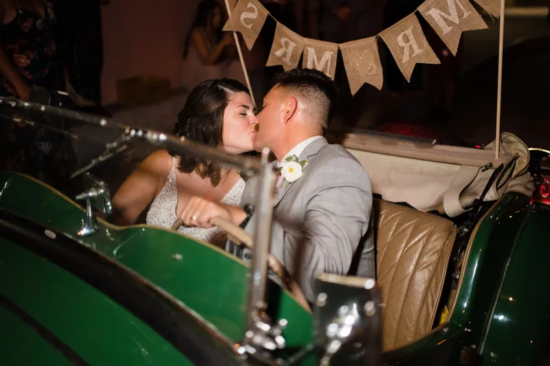 Laurel and Jake kiss in a vintage green convertible decorated with a "Just Married" banner.