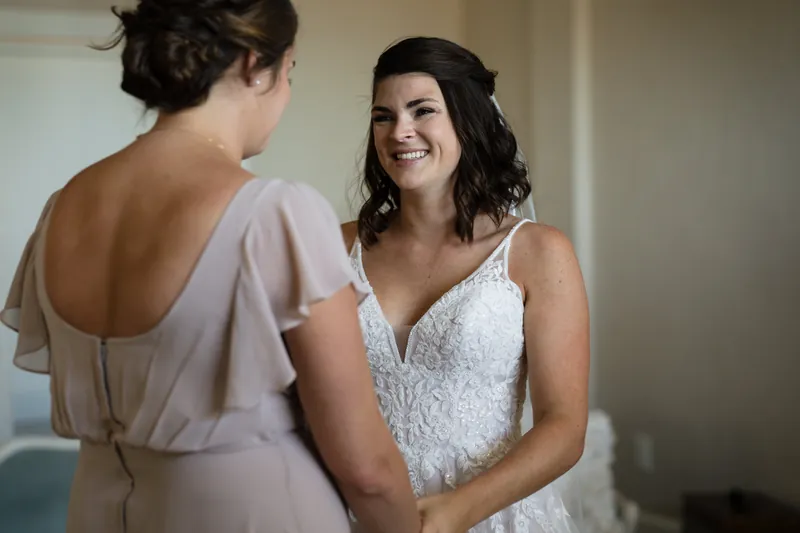 Laurel smiles while chatting with a bridesmaid in a beaded gown at The White Room.