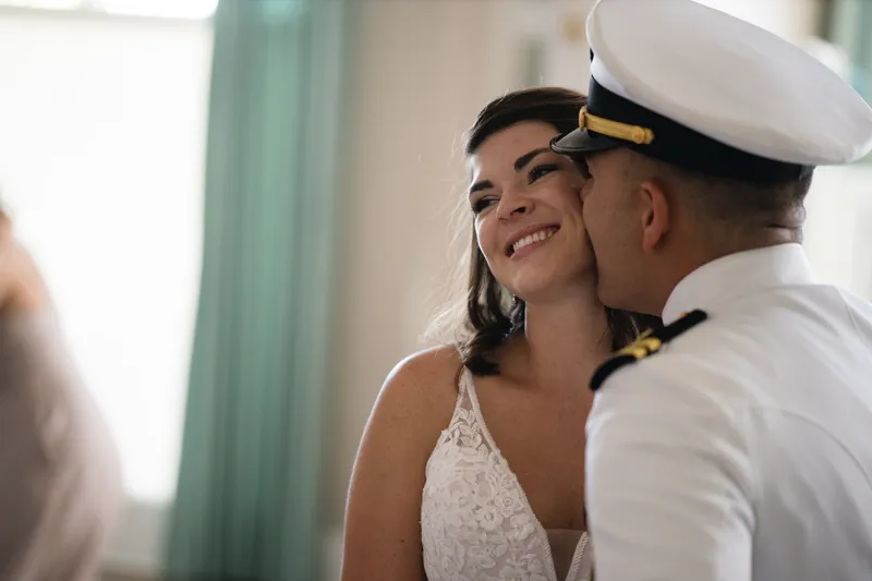 Laurel laughs as Jake in his white naval uniform leans in to kiss her cheek at The White Room.