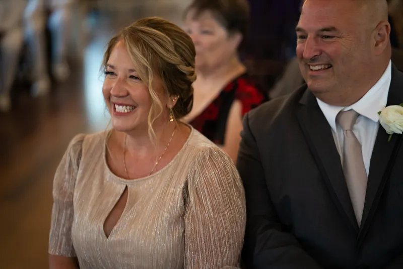 Laurel and a male guest laugh together during the reception, both smiling warmly at the moment.