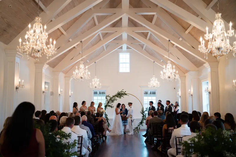 The newlyweds walk back down the aisle together through the white chapel as attendees rise to applaud.