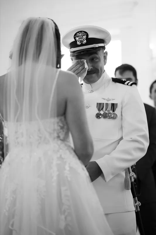 Jake in uniform gazes at Laurel's veiled face during their ceremony at The White Room.