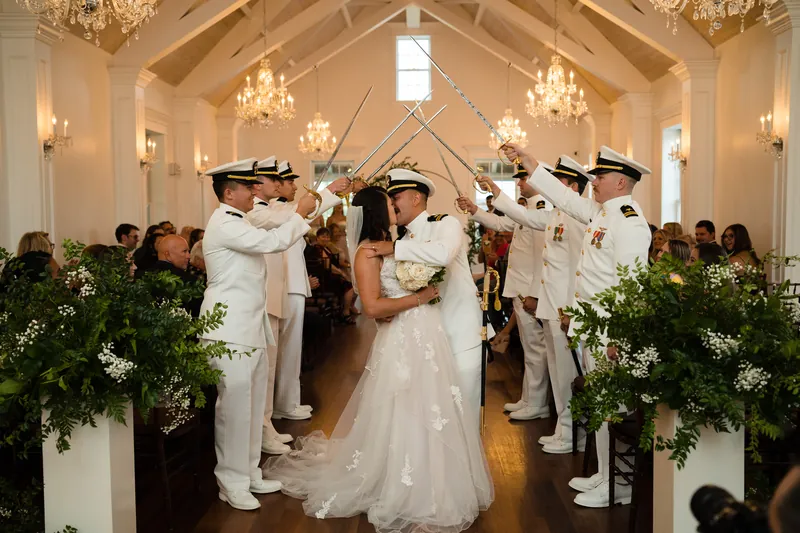 Laurel ducks under the raised sabers while Jake smiles during the traditional military sword arch.