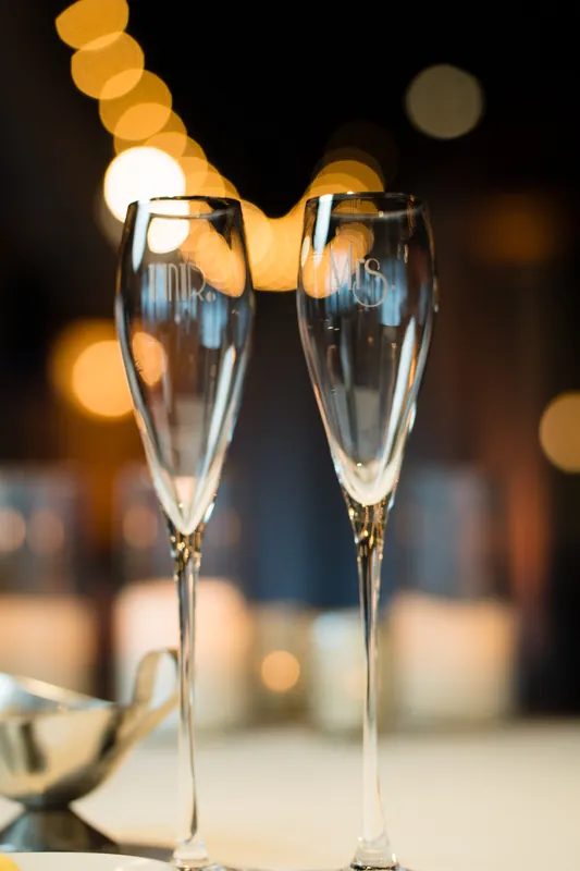 Candlelit reception table features water glasses and white linens with soft amber lights glowing beyond.