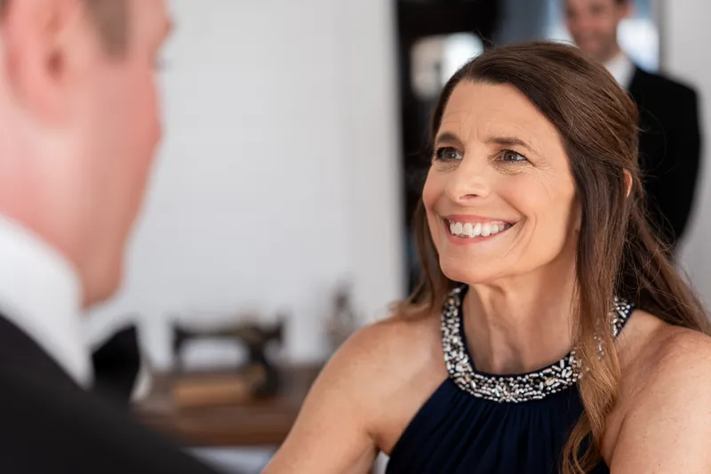 Lauren smiles warmly while conversing with a man in formal attire at Beaches Museum Chapel.