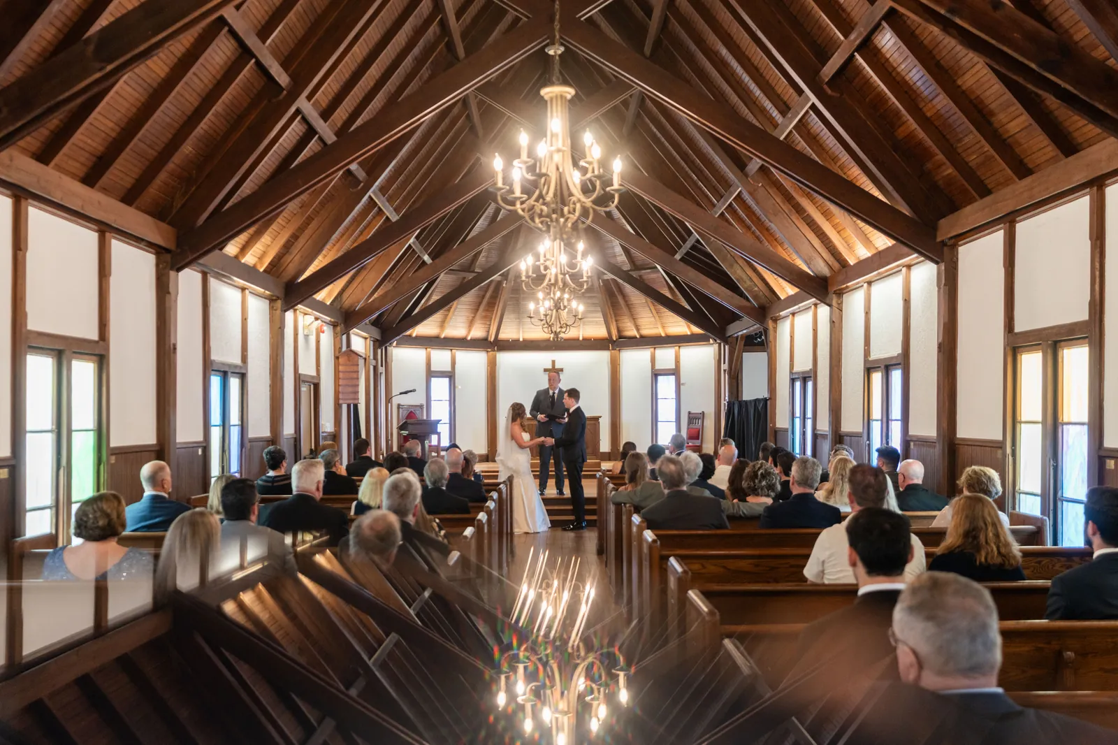 The chapel's vaulted wooden interior with chandeliers as guests watch Lauren and Kevin exchange vows.