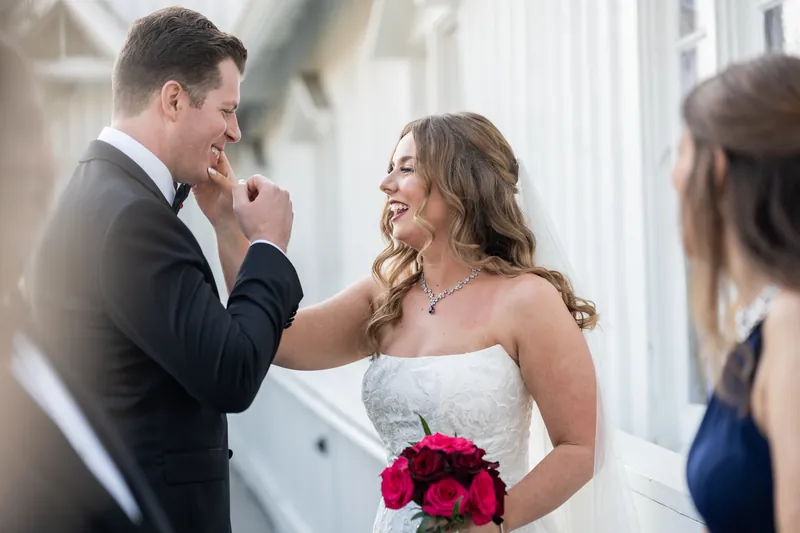Kevin playfully touches Lauren's face as they laugh together, her white strapless gown and hot pink flowers visible.
