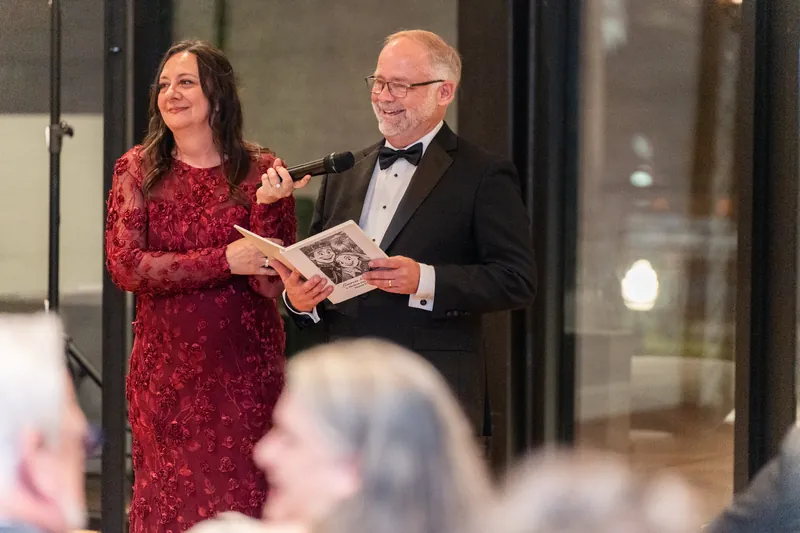 Lauren in a crimson lace dress and Kevin in a tuxedo hold a program during the reception at Private 131, Jacksonville.