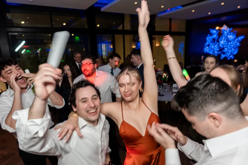 Kevin and male guests celebrate enthusiastically with raised arms and bright expressions during dancing.