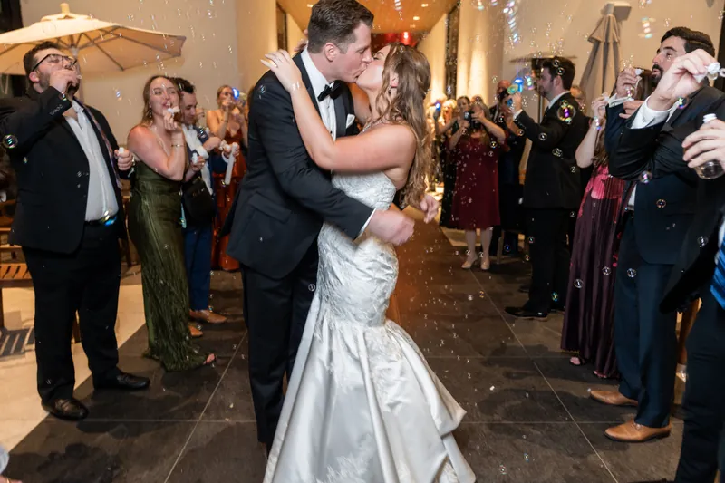Lauren and Kevin dance together at their reception as guests surround them in formal attire, with confetti falling around