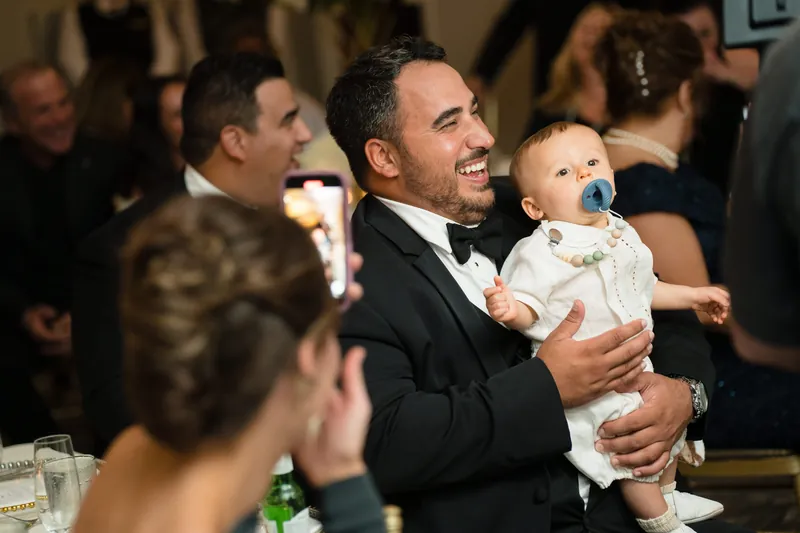 Cole holds a small child and smiles while speaking to guests at the reception.