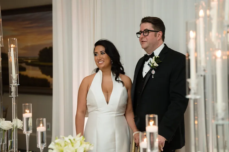 Lehna in a white halter gown and Cole in a black tuxedo stand by illuminated candles at Casa Monica Resort & Spa.