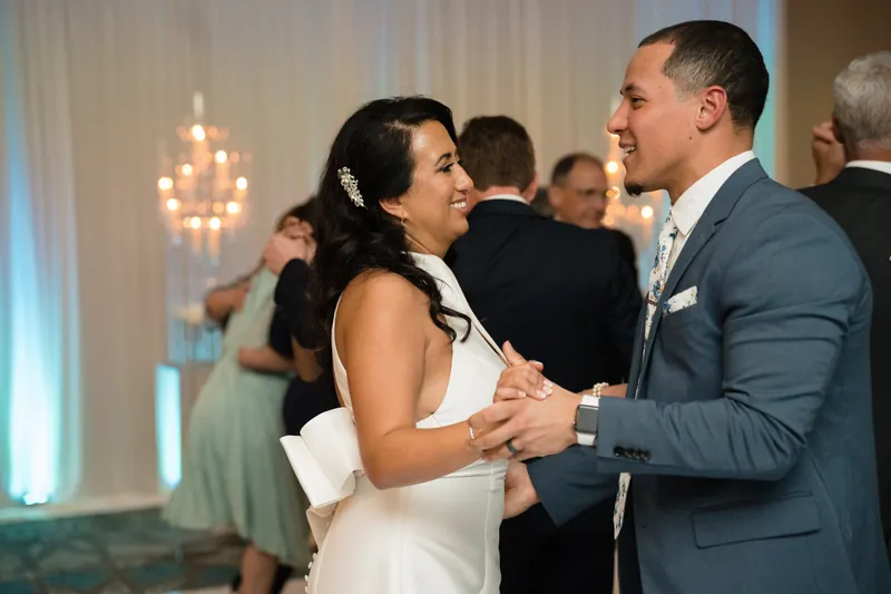 Lehna and Cole dance together at Casa Monica Resort & Spa, with hanging pendant lights and guests visible in the warm