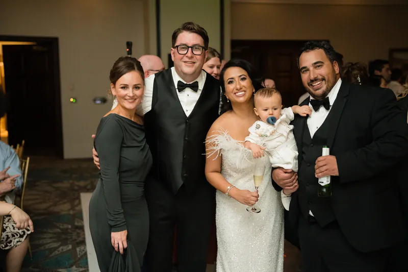 Cole stands with Lehna, a young child, and two other guests in formal attire at the reception.