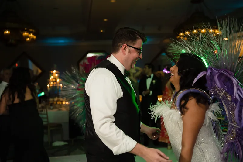 Cole and a guest dance together at Casa Monica Resort & Spa, surrounded by purple feathered costumes and warm lighting.