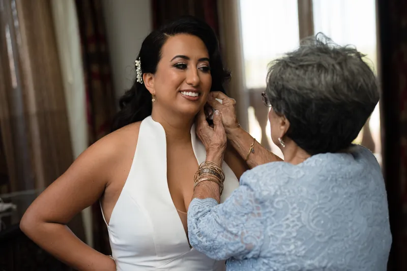 An older woman fastens Lehna's earring while Lehna smiles at the Cathedral Basilica of St. Augustine.