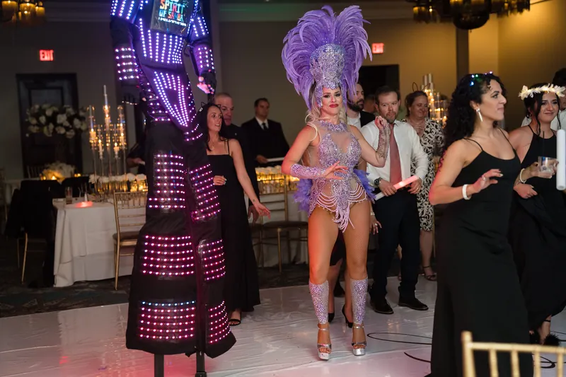 A performer in a shimmering purple sequined outfit commands attention while guests in formal wear watch from across Casa