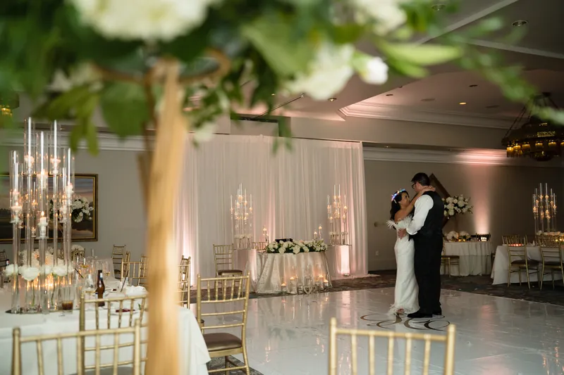 Lehna and Cole embrace during their first dance beneath dramatic white draping and glowing candelabras.