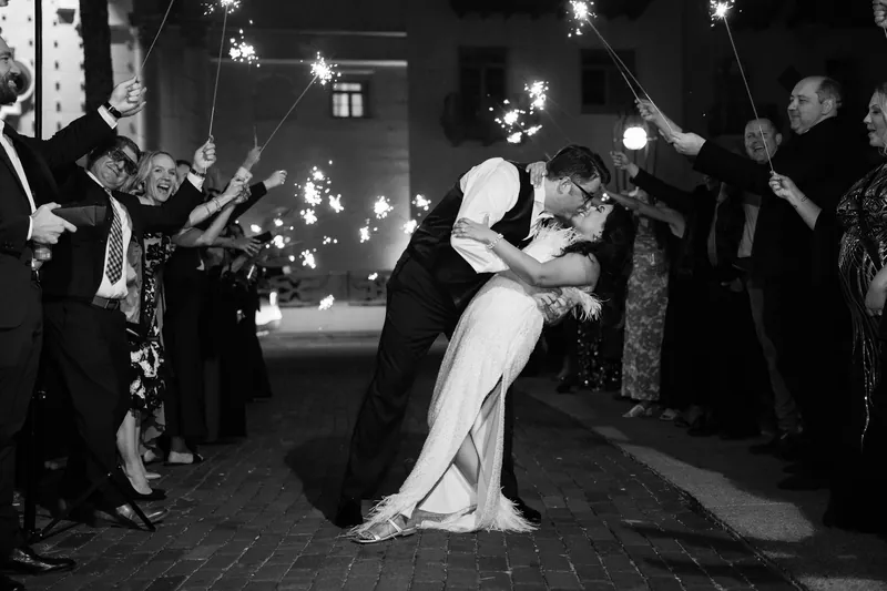 Cole dips Lehna under a shower of sparklers as guests celebrate their exit in black and white.