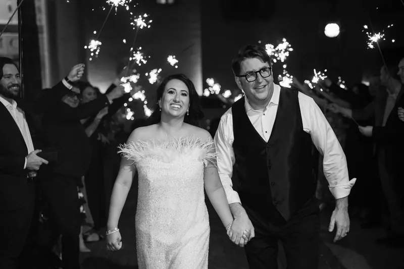Lehna and Cole walk hand in hand through Casa Monica Resort & Spa as sparklers light the night sky around them in black