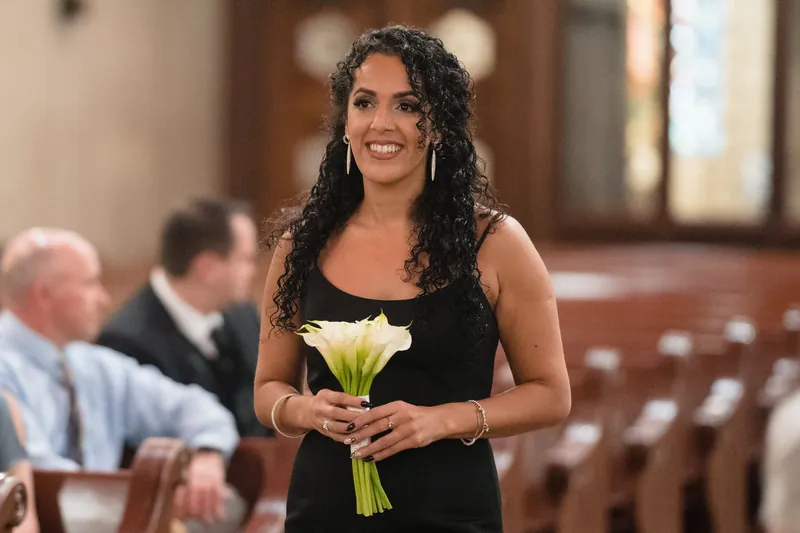 Lehna holds white calla lilies while smiling at the Cathedral Basilica of St. Augustine during the ceremony.