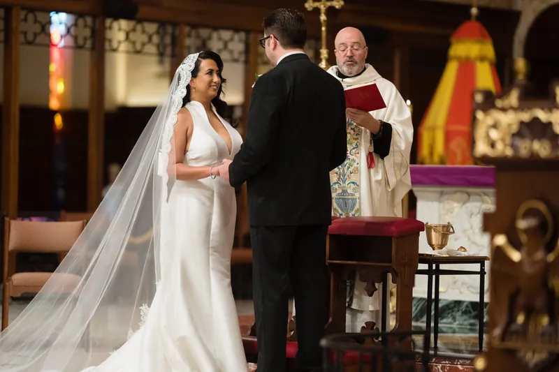 Lehna's long veil trails behind as she and Cole exchange vows with the priest presiding at the altar.
