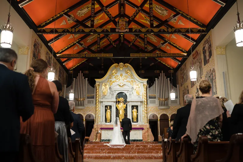 Lehna and Cole exchange vows beneath the ornate golden altar at Cathedral Basilica of St. Augustine, with guests seated