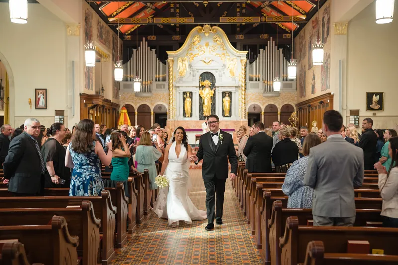 Lehna and Cole walk back down the center aisle of the Cathedral Basilica as guests stand and celebrate their exit