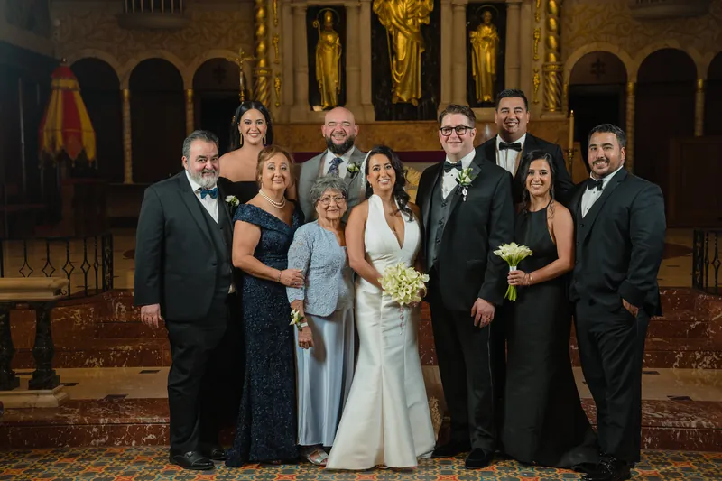 The wedding party gathers at the basilica's ornate altar—Lehna and Cole flanked by family members in formal attire, all