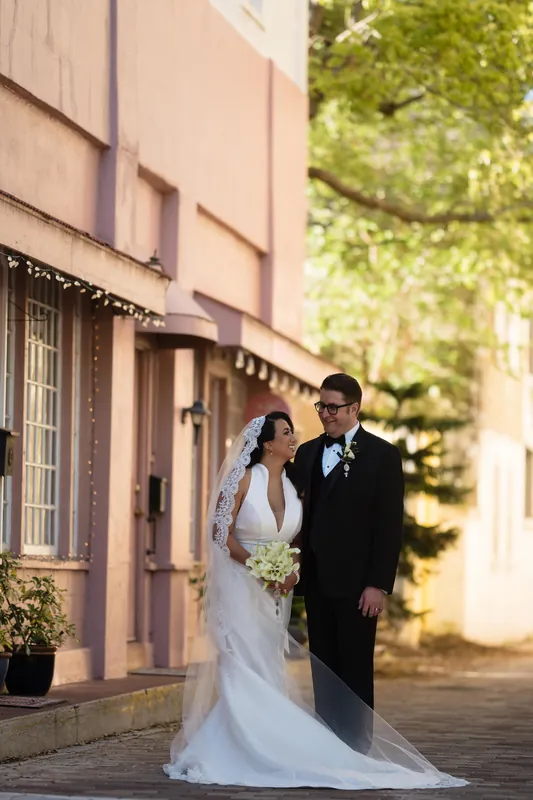 The couple walks along the resort's colonnade, Cole in formal wear beside Lehna in her white wedding dress and long train.