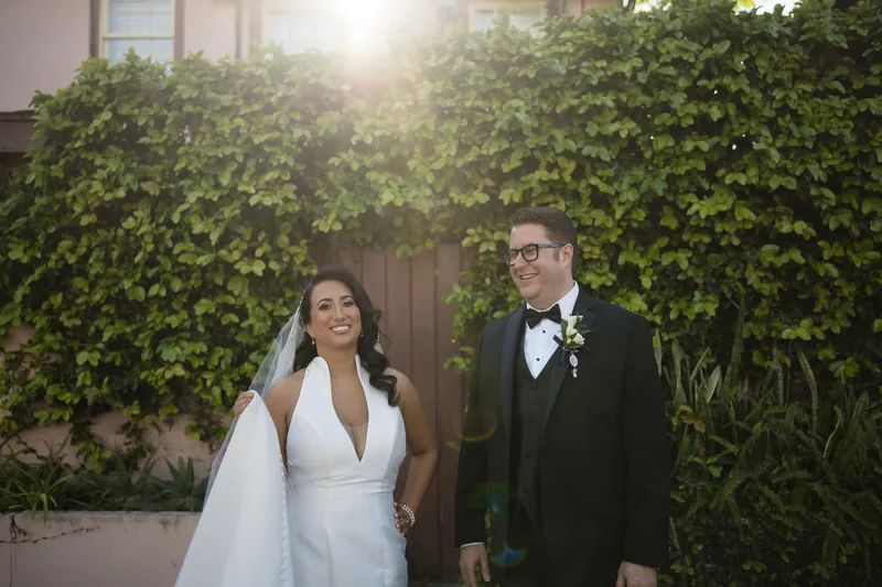 Lehna and Cole stand before ivy-covered architecture at the resort, backlit by golden afternoon light.