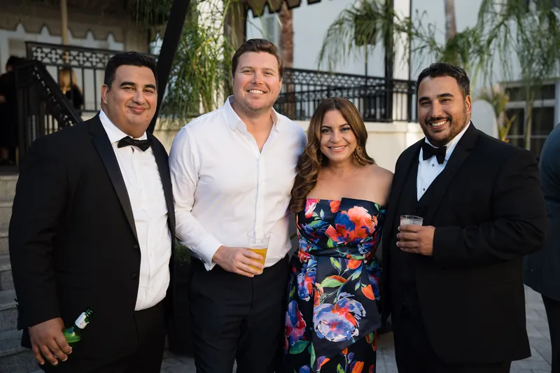 Four guests in formal attire smile while posing together on the resort's terrace.