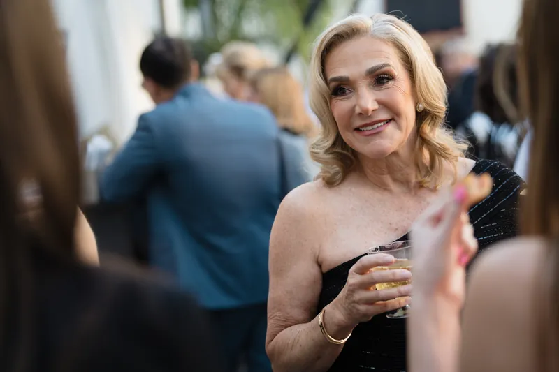 A woman in a strapless beige dress holds a cocktail while mingling with guests at Casa Monica Resort & Spa.