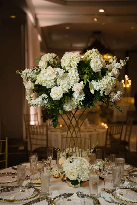 A tall glass vase overflows with white hydrangeas and roses above a formally set dining table at Casa Monica Resort & Spa.