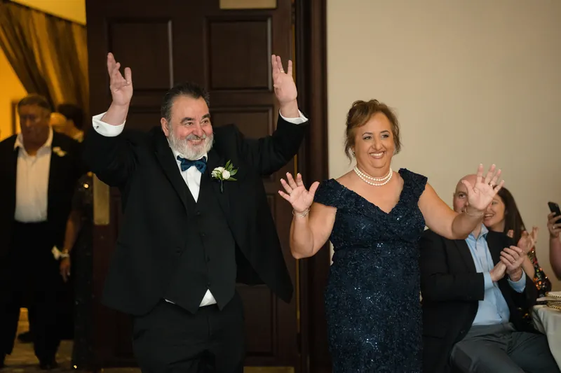 Two guests celebrate with raised arms and joyful expressions during the reception.