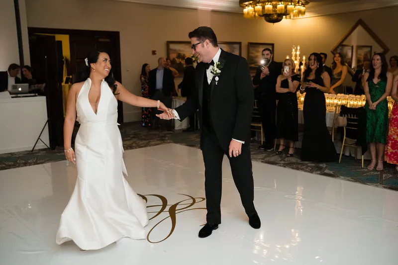 Lehna in a flowing white gown and Cole in a black tuxedo share their first dance on the ballroom floor.