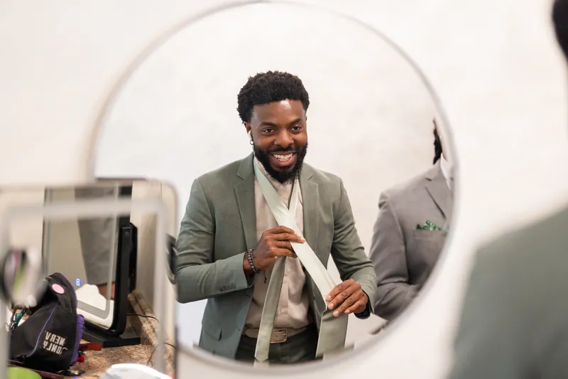 Blake smiles while adjusting his tie in a mirror at Fountain of Youth Archaeological Park.