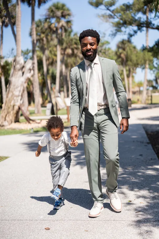 Blake walks hand-in-hand with a young child down a palm-lined path at Fountain of Youth Archaeological Park.