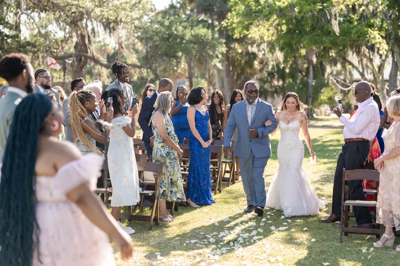Lena and Blake exchange vows beneath towering oaks with Spanish moss while their guests gather around them at the outdoor