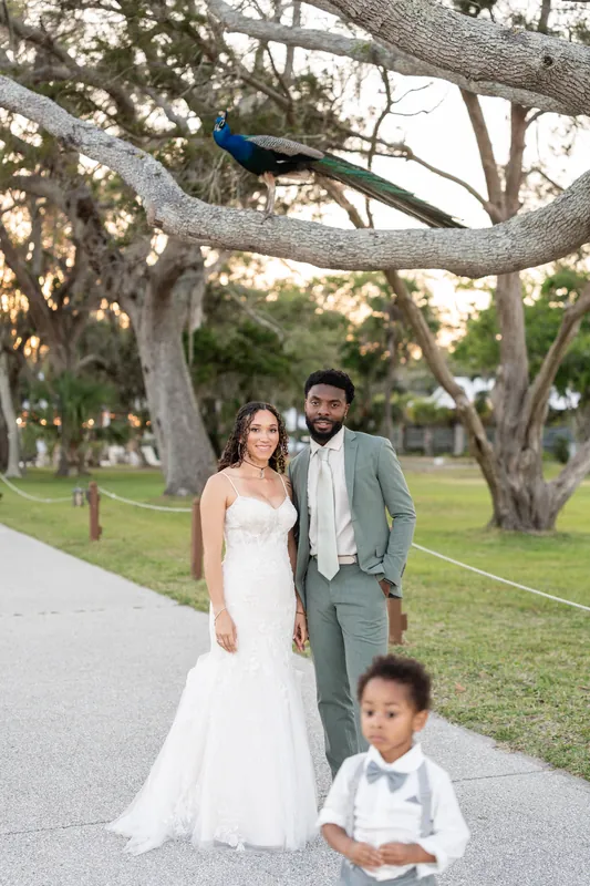Blake and Lena walk under sprawling oak trees with their young son on the manicured grounds at Fountain of Youth