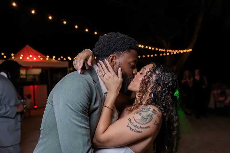Blake and a guest kiss under glowing overhead lights during the evening celebration at Fountain of Youth Archaeological Park