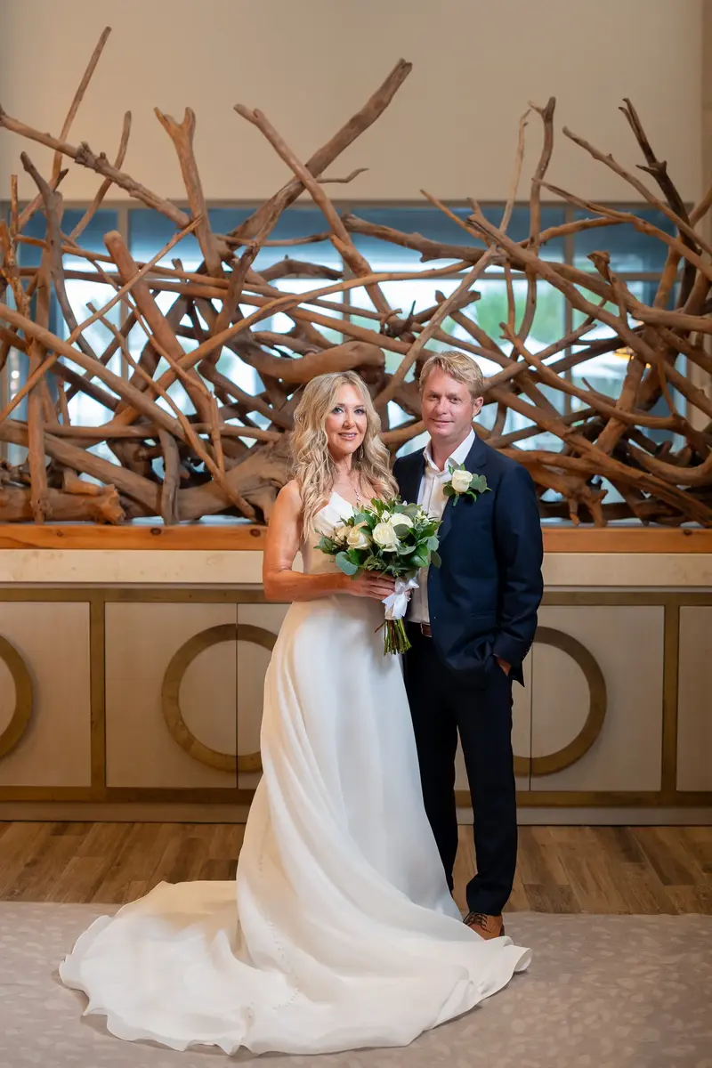 Bride and groom portrait in front of driftwood art installation