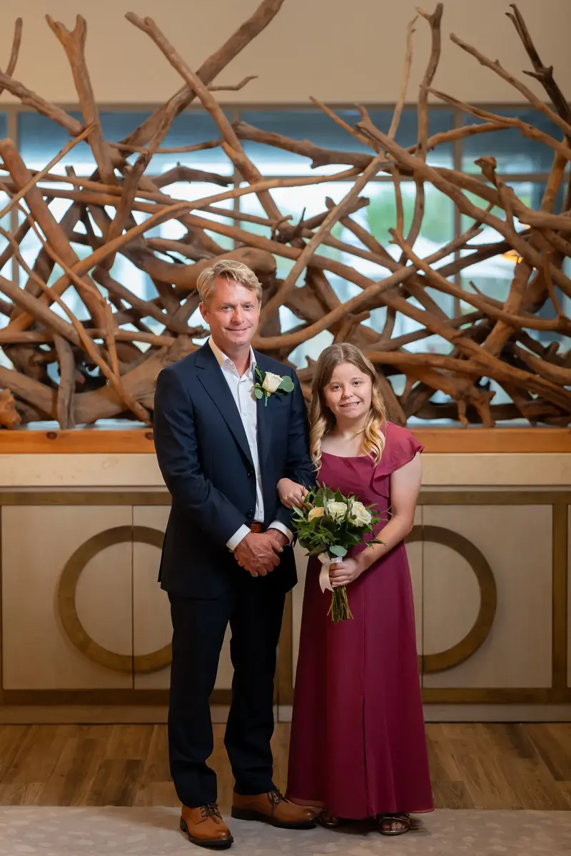 Groom with daughter in front of driftwood sculpture