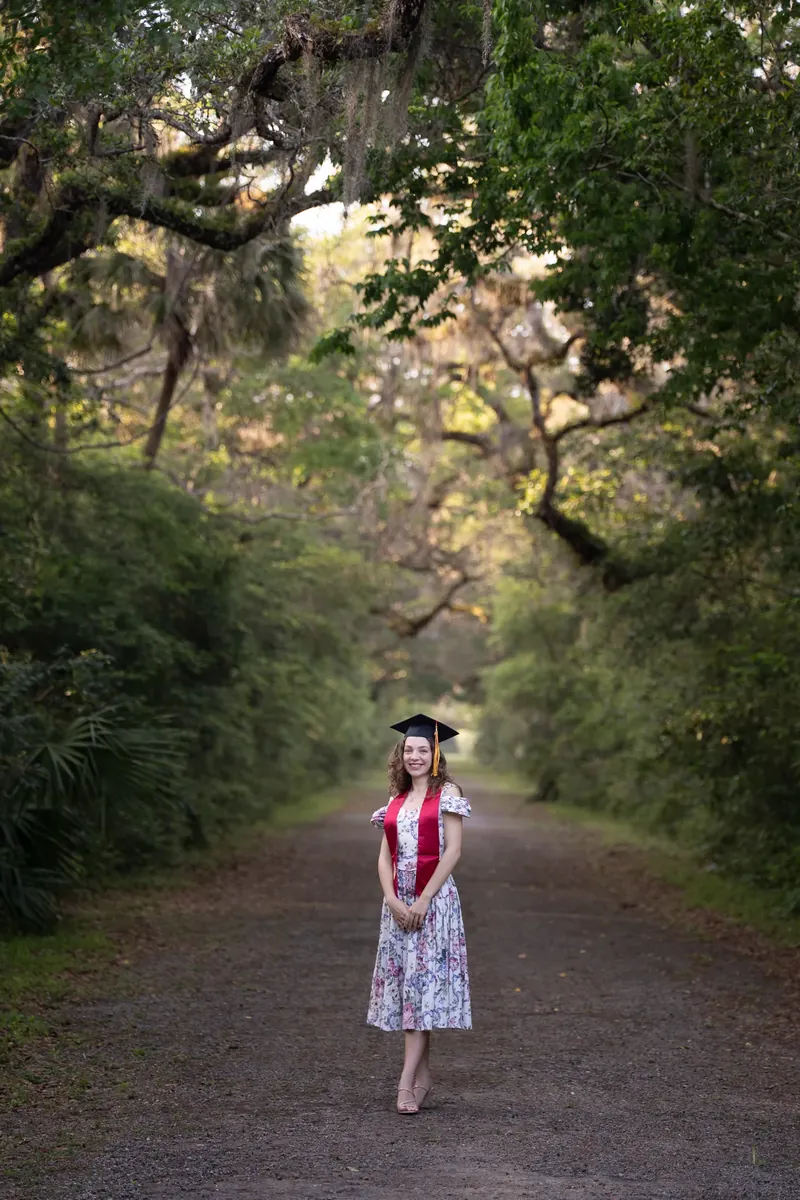 Lydia in graduation cap under oak tree canopy at Washington Oaks