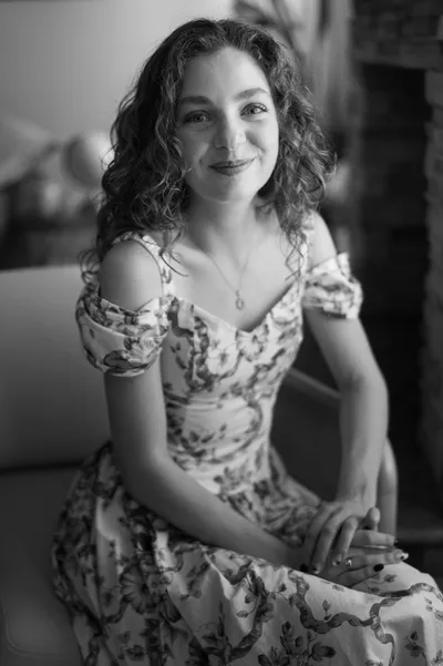 Woman in floral dress smiling at camera, black and white portrait