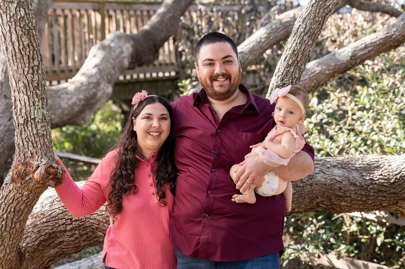 Young couple with their baby girl by the oak tree
