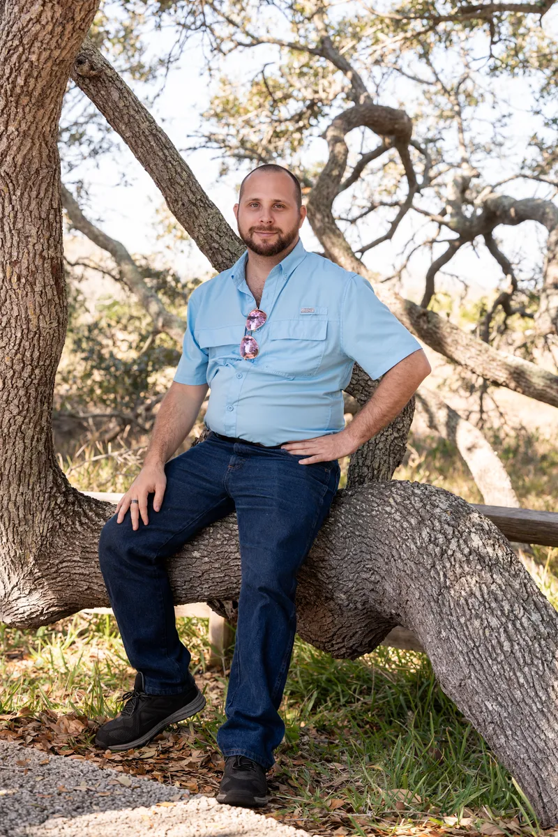 Man sitting casually on a large oak tree branch at Nease Park