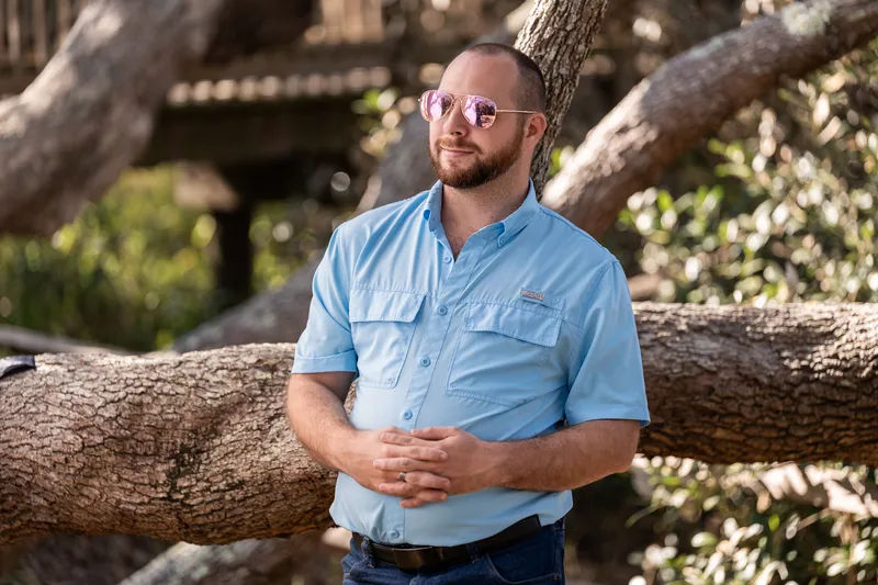 Man in sunglasses leaning against an oak tree branch at Nease Park